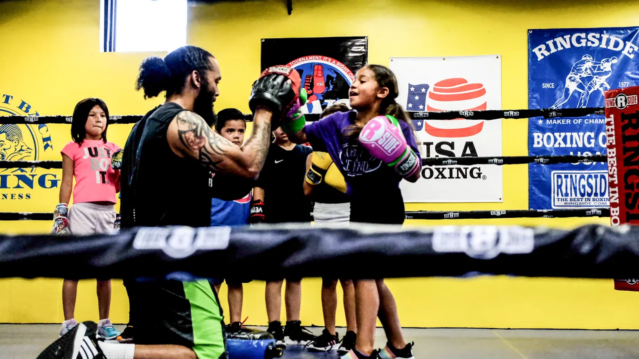 Coach Hector Saez working one-on-one with a young boxer